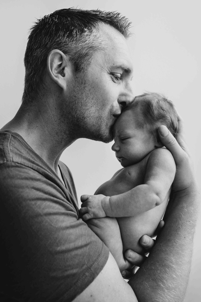 Vader geeft kus op het hoofd van zijn baby