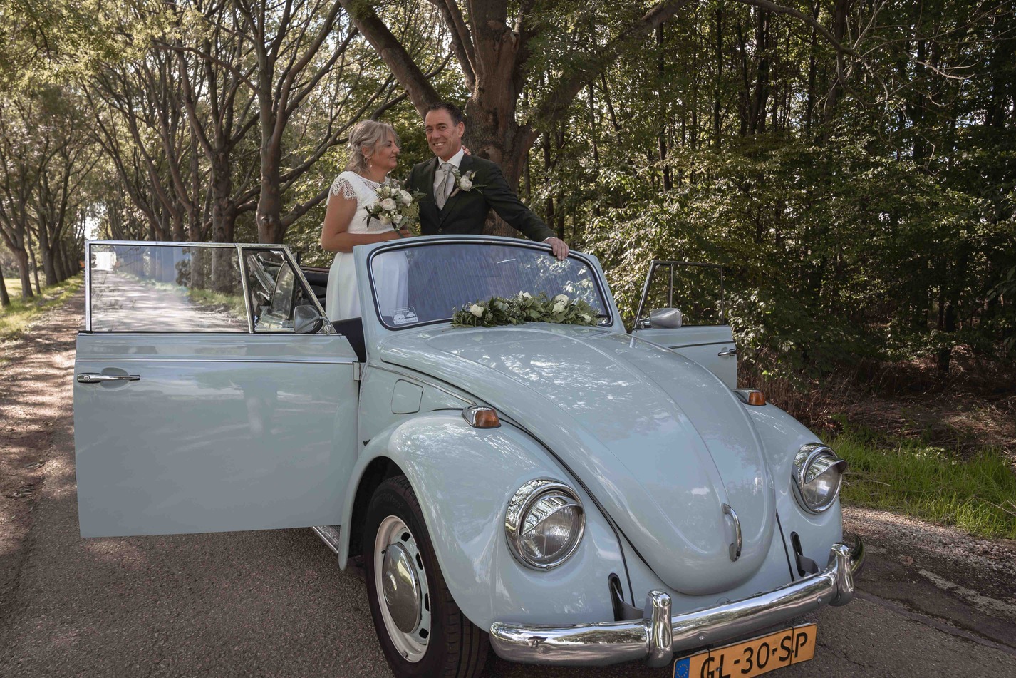 Bruid en bruidegom in auto met open deur