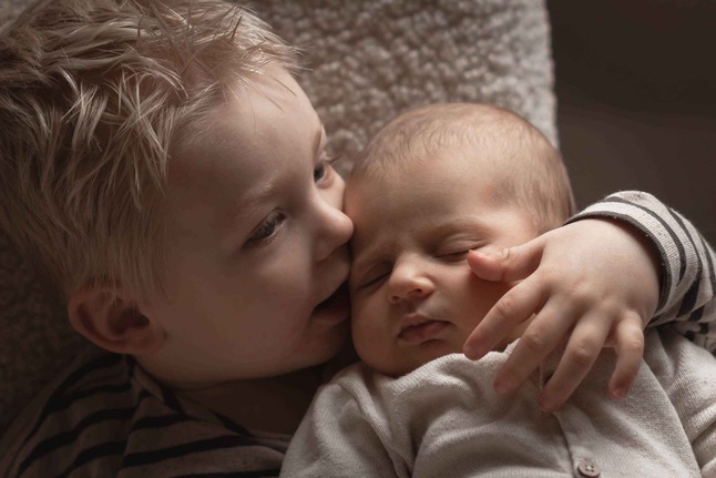 Broertje ligt met baby op zijn borst