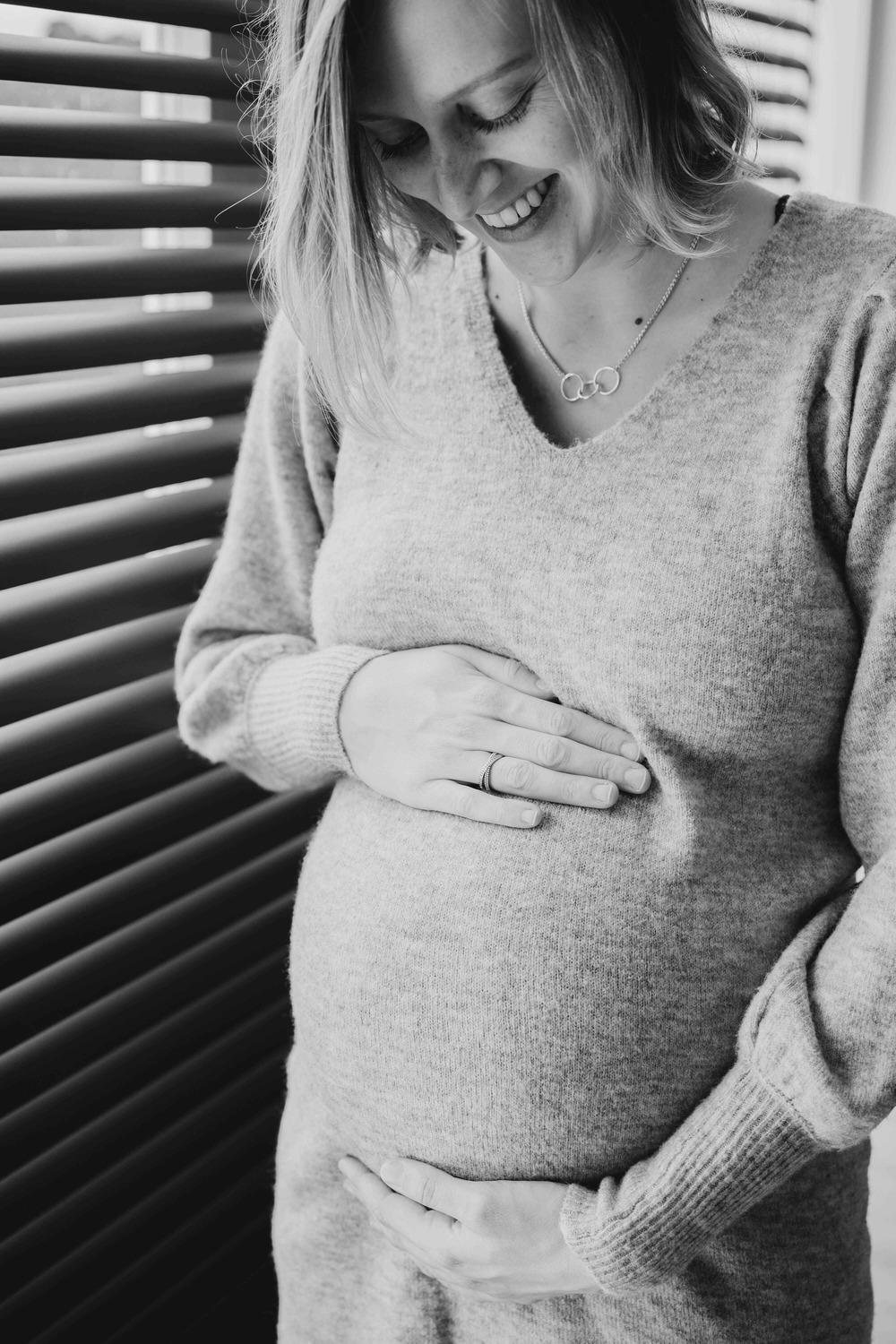 Zwangere vrouw heeft handen op haar buik in zwart wit