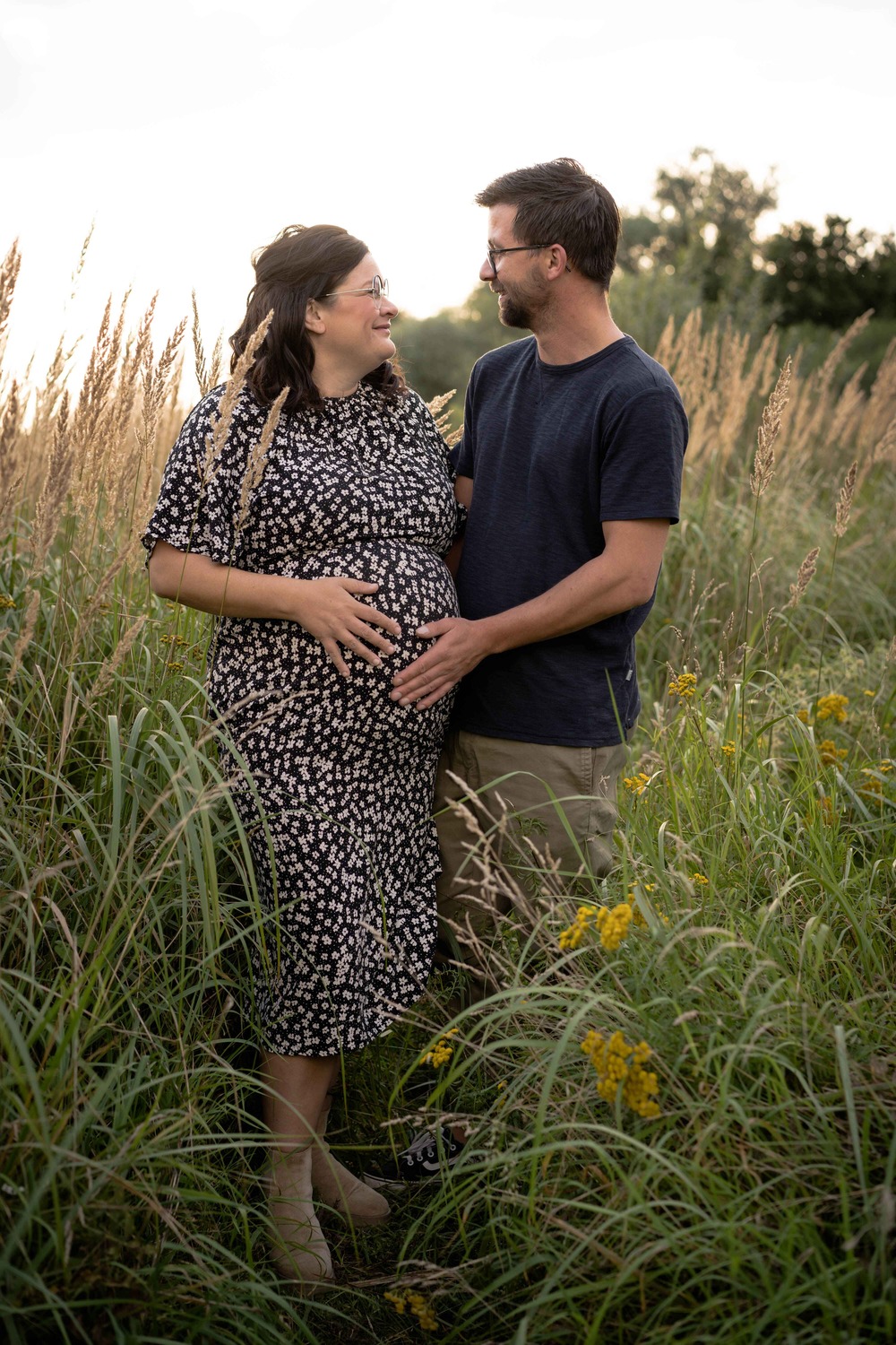 Man en zwangere vrouw staan tussen hoge planten