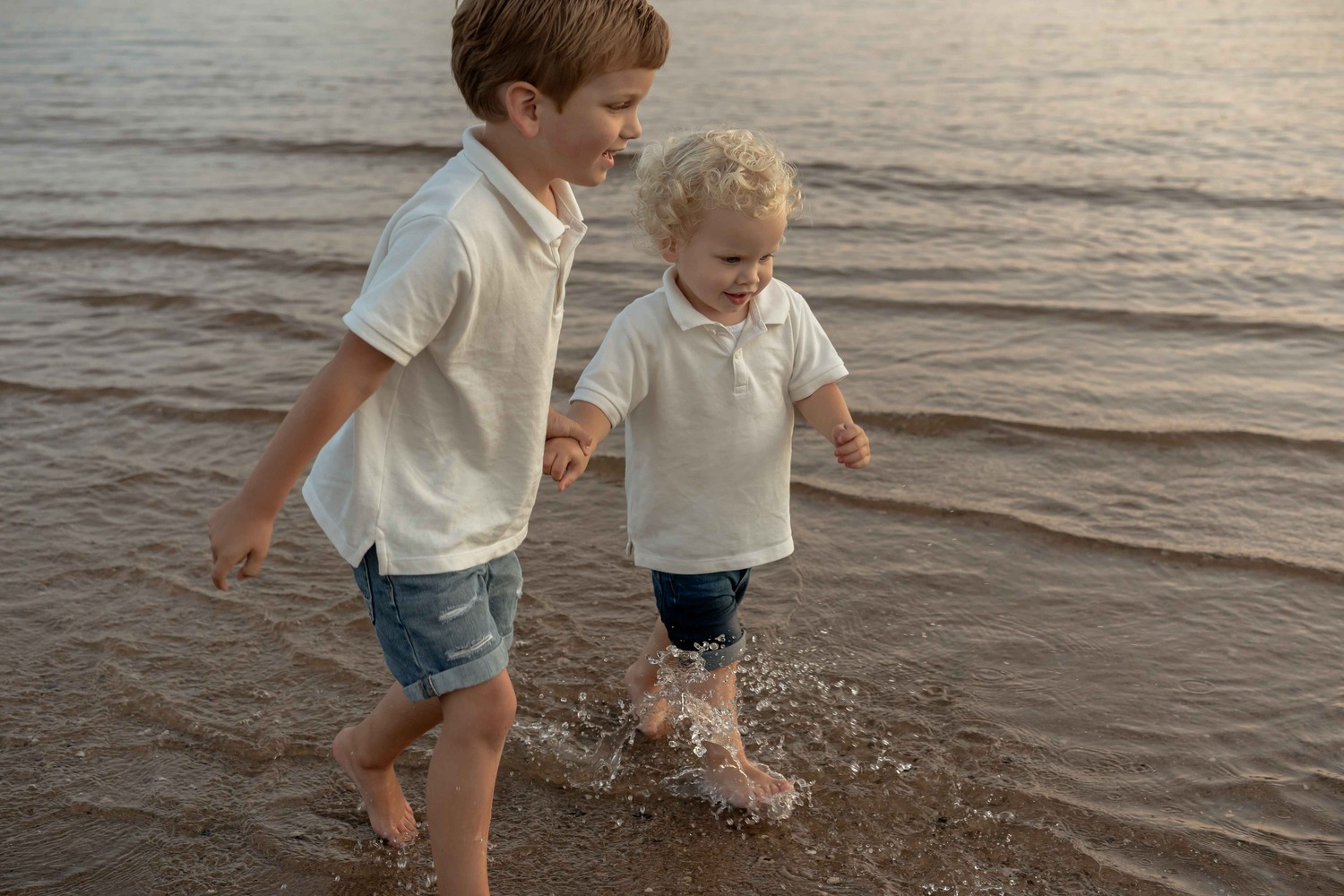 Twee broertjes rennen naar de camera door het water