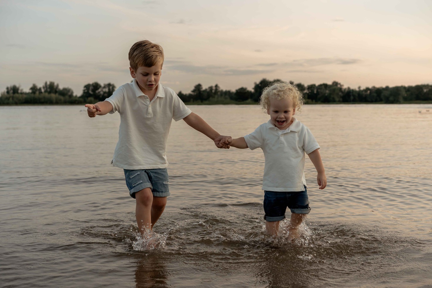 Twee broertjes lopen naar de camera door het water heen