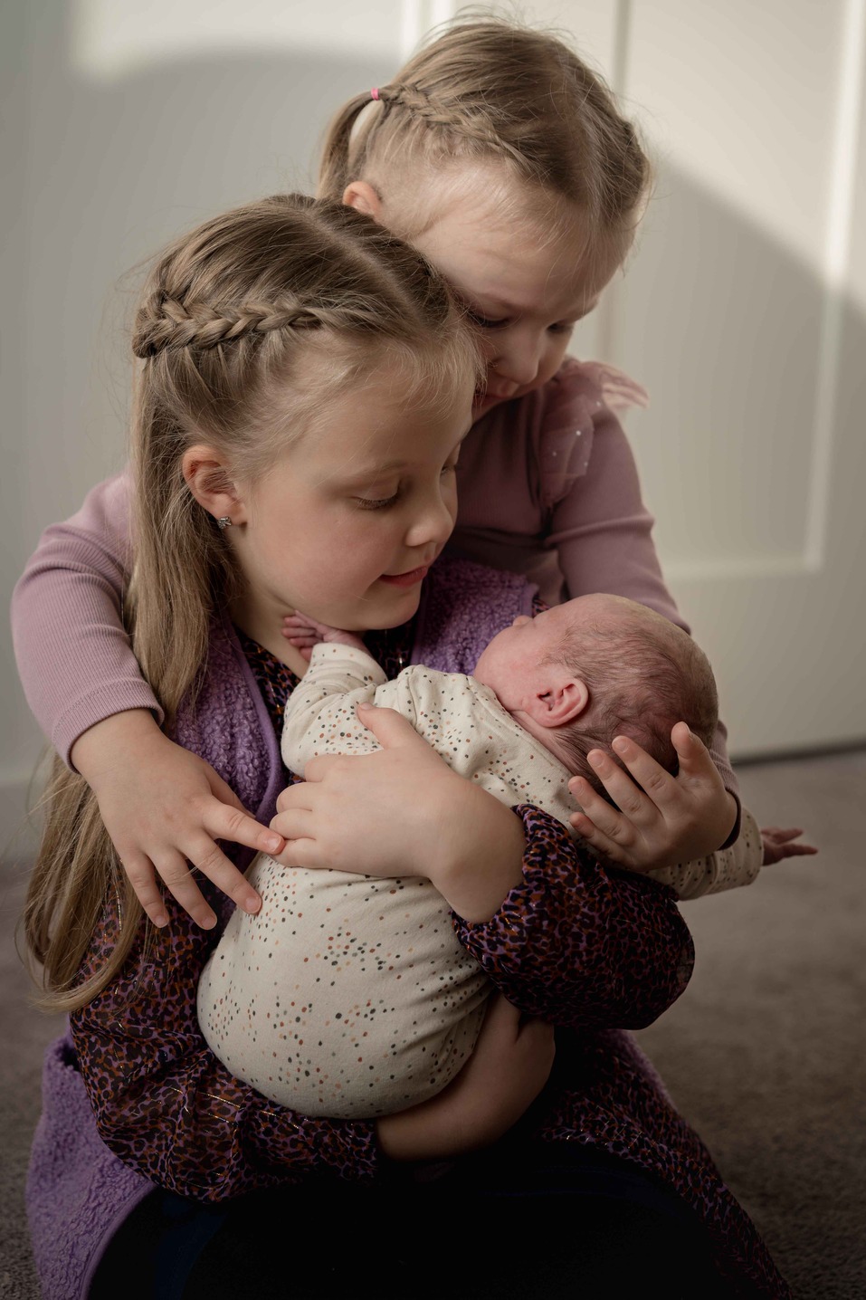 Twee zusjes hebben een baby vast