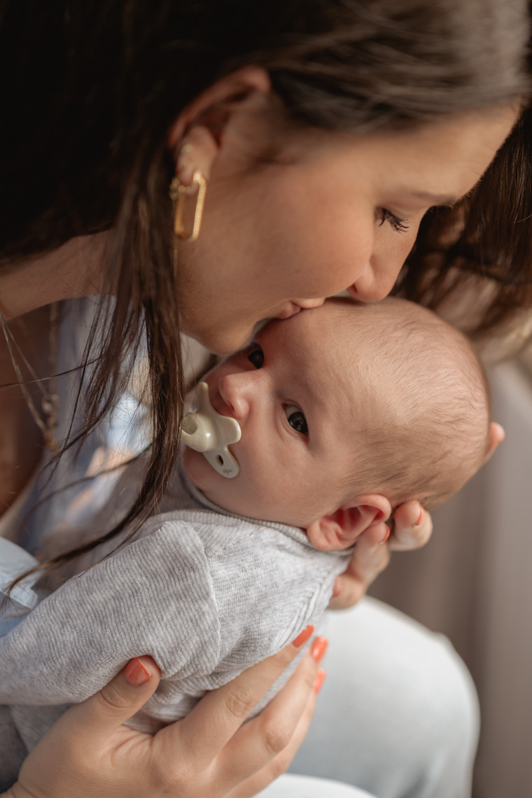 Moeder geeft kus op baby zijn hoofd
