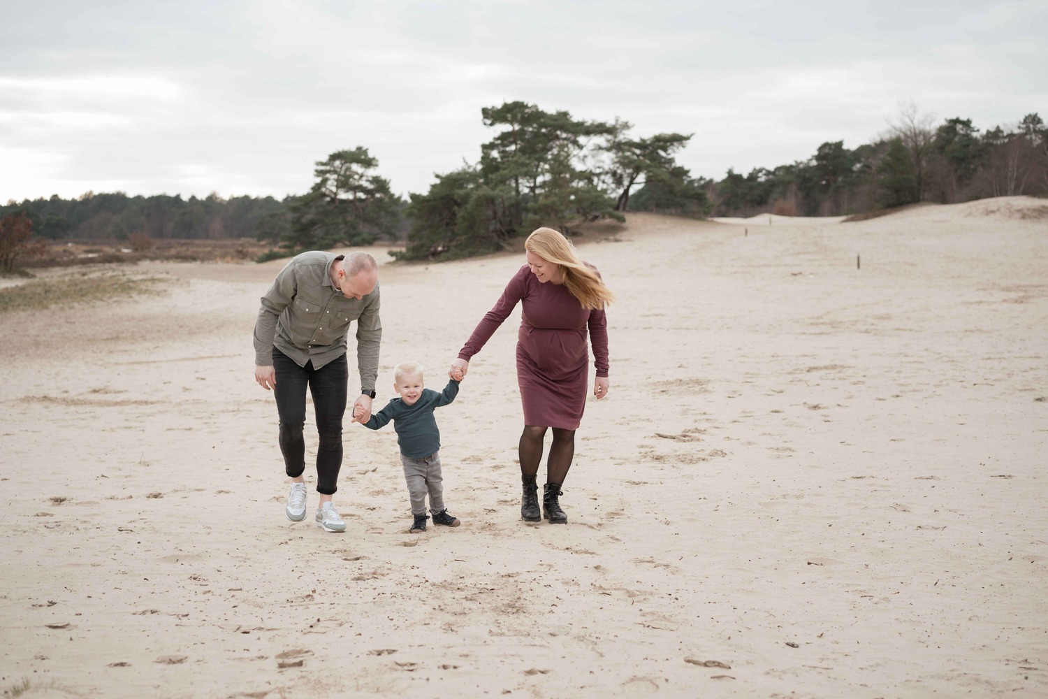 Vader moeder en en kind lopen op een zandvalkte